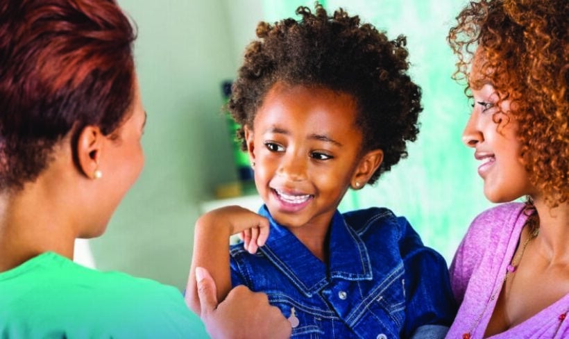 Smiling women and a young girl being held by one woman and interacting with them