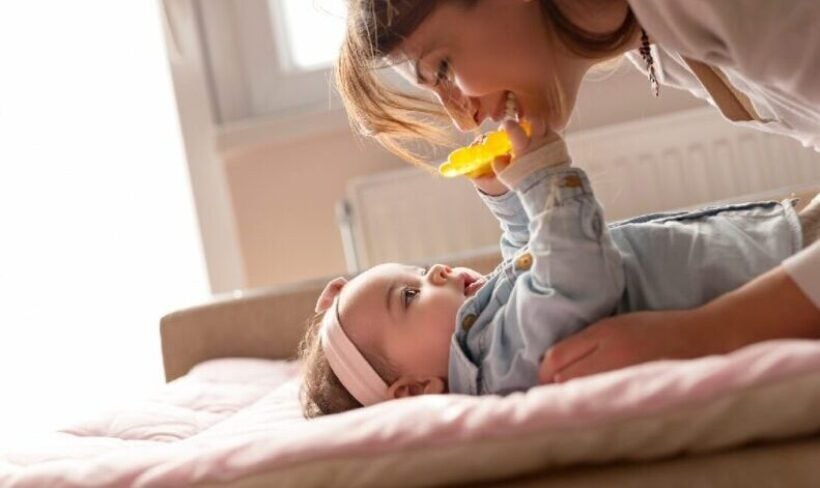 A mother smiling playfully and interacting with her infant