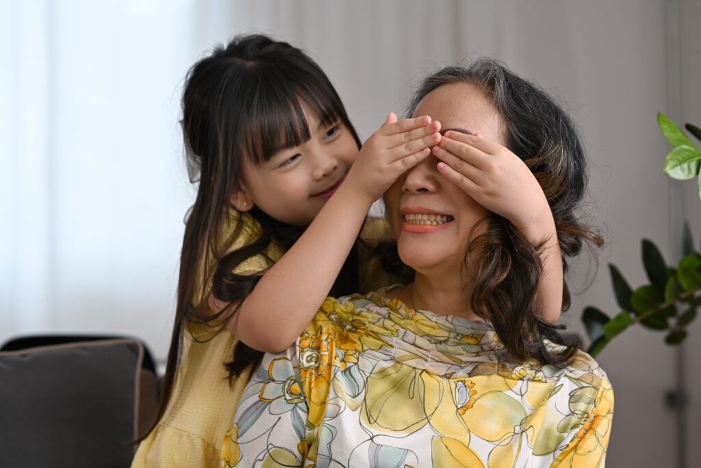 A little girl playing peek-a-boo over her grandmother's eyes