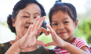 Asian Grandmother And Little Child Girl Making Heart Shape With Hands Together With Love