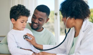 African dad, child and woman doctor with stethoscope in doctors office for health checkup on heart, lungs and breathing. Black man, son and pediatrician in healthcare checking kids asthma symptoms.