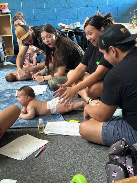 Parents seated on the ground and playing with their babies at the Legacy Parenting Center in Shawnee, OK