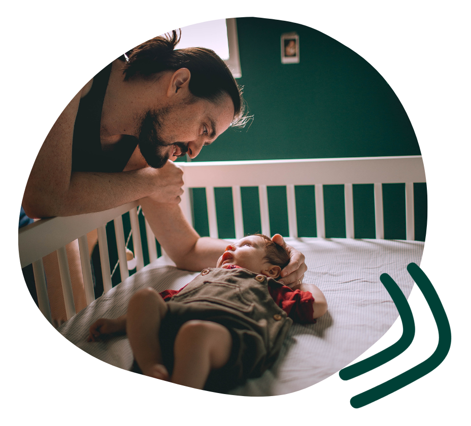 Father leaning over side of cradle to comfort infant